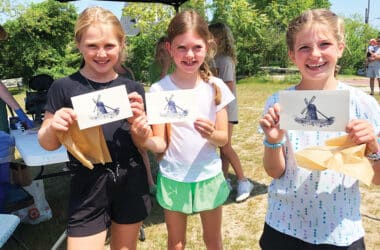 Three girls proudly display their windmill prints made at a hands-on craft station during NHA Community Day, a free family event on Nantucket.