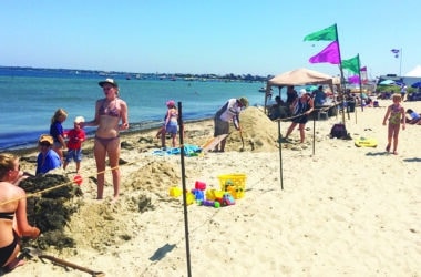 Families building creative sand sculptures during the NISDA Sandcastle & Sandsculpture Contest at Jetties Beach