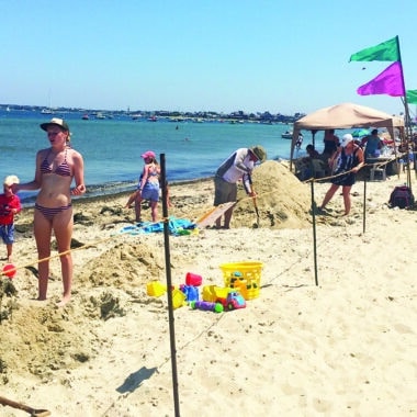 Families building creative sand sculptures during the NISDA Sandcastle & Sandsculpture Contest at Jetties Beach