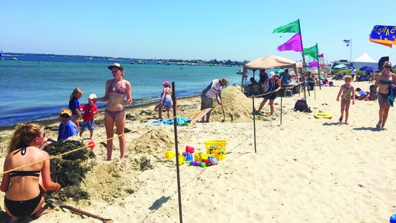 Families building creative sand sculptures during the NISDA Sandcastle & Sandsculpture Contest at Jetties Beach