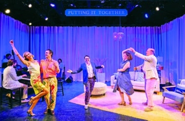 The cast of Putting It Together dances and performs on stage at the Theatre Workshop of Nantucket, with the show's title sign lit above a coastal mansion set.