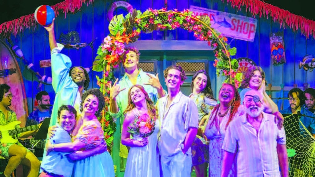 The cast of Theatre Workshop of Nantucket's Escape to Margaritaville poses on the show's vibrant tropical set.