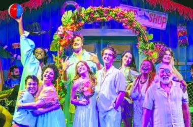 The cast of Theatre Workshop of Nantucket's Escape to Margaritaville poses on the show's vibrant tropical set.