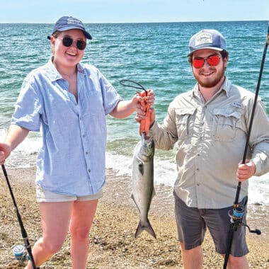 Nantucket musician Gabe Zinzer and fiddler Emma Buckner hold up a bluefish caught during her visit to Great Point.