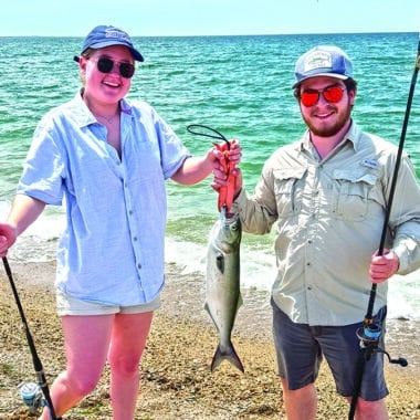 Nantucket musician Gabe Zinzer and fiddler Emma Buckner hold up a bluefish caught during her visit to Great Point.