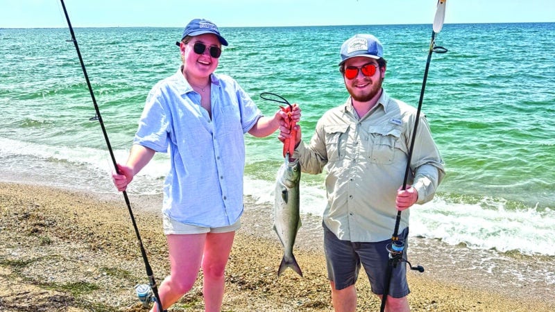 Nantucket musician Gabe Zinzer and fiddler Emma Buckner hold up a bluefish caught during her visit to Great Point.