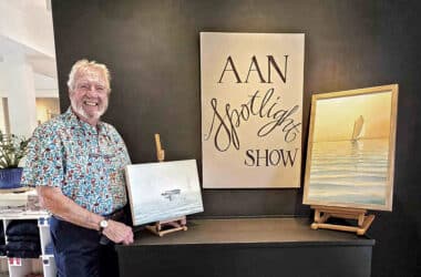 Nantucket artist G.S. Hill stands beside two of his oil paintings on display for the AAN Spotlight Series show.