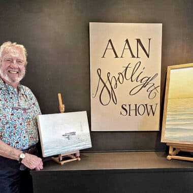 Nantucket artist G.S. Hill stands beside two of his oil paintings on display for the AAN Spotlight Series show.