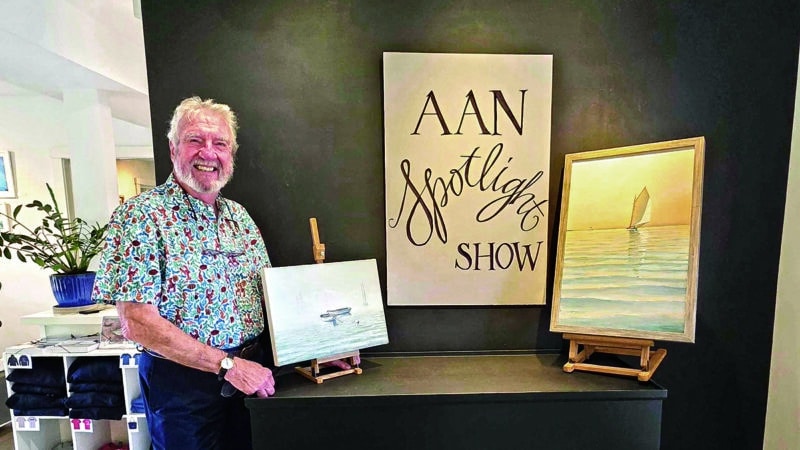 Nantucket artist G.S. Hill stands beside two of his oil paintings on display for the AAN Spotlight Series show.