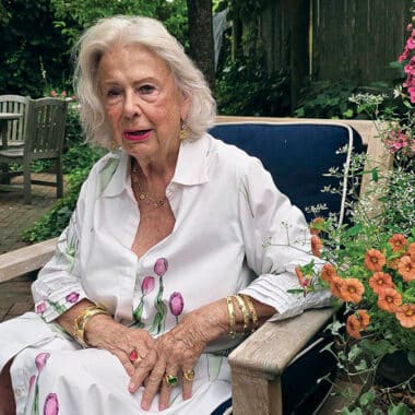 Nantucket jeweler Susan Lister Locke sits in her garden wearing gold bracelets and rings from her own collection.