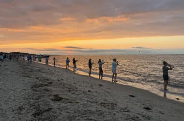Women line the shoreline casting at sunset during Tammy King's annual women's fishing seminar on Nantucket.