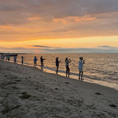 Women line the shoreline casting at sunset during Tammy King's annual women's fishing seminar on Nantucket.