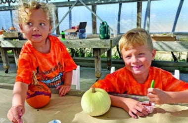Two children painting pumpkins during a fall family activity at Bartlett's Farm on Nantucket.