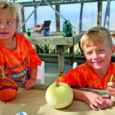 Two children painting pumpkins during a fall family activity at Bartlett's Farm on Nantucket.