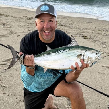 Angler holding a false albacore caught while surfcasting on a Nantucket beach.